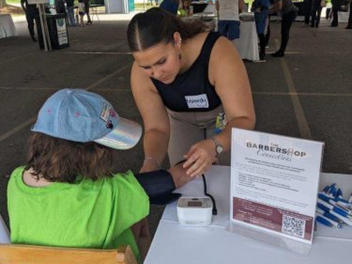 Woman checking the blood pressure of a child in a green shirt