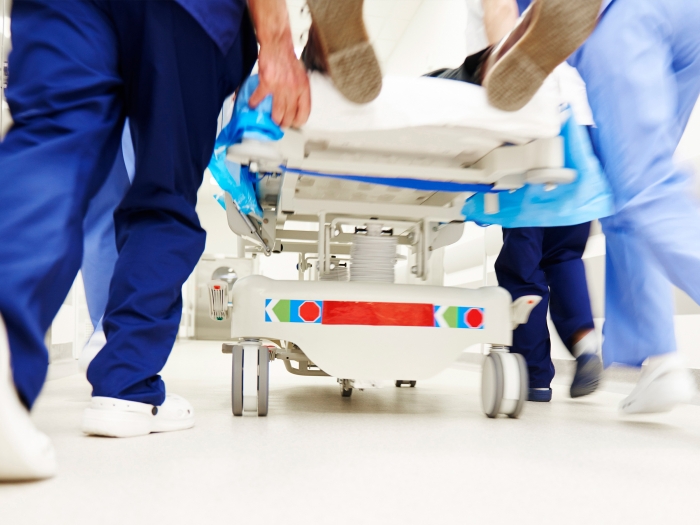 white sneaker feet in dark blue and light blue scrubs rushing a hospital bed into medical area