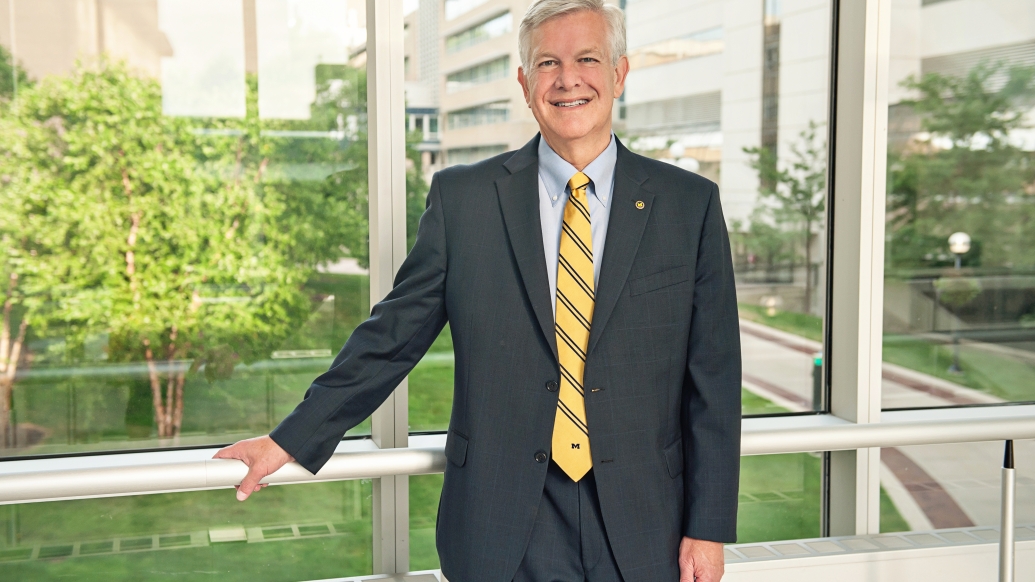 Marschall S. Runge, M.D., Ph.D., poses in a blue suit and yellow tie on the Michigan Medicine campus.