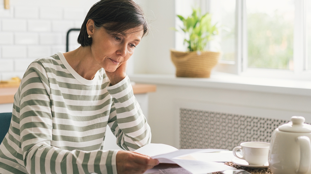 woman sitting at table in stripe shirt stressed seeming white background window