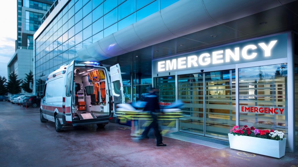 emergency room front doors with sign and blurred motion of people and a vechile