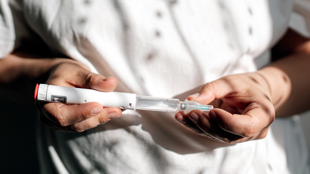 holding syringe white shirt close up in hands