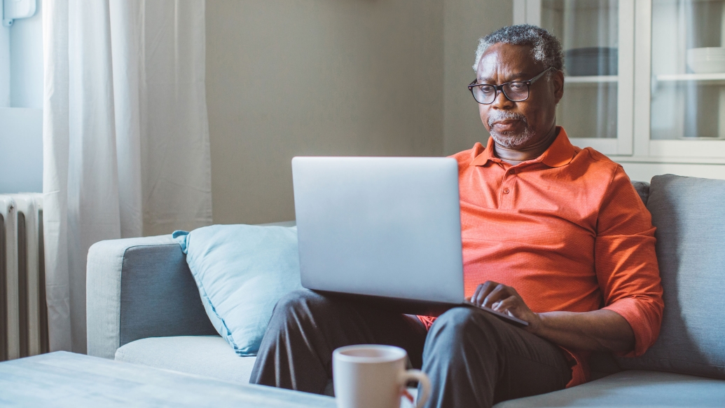 man in orange shirt sitting in living room