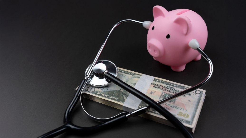 pink little pig bank listening to money with a stethoscope on a black table