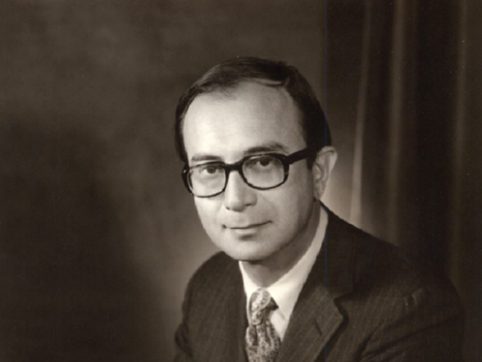 Vintage looking black and white portrait of a middle aged white man wearing a suit and glasses