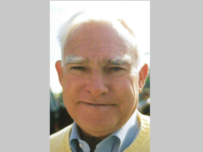 An older white man wearing a blue button down shirt and yellow sweater