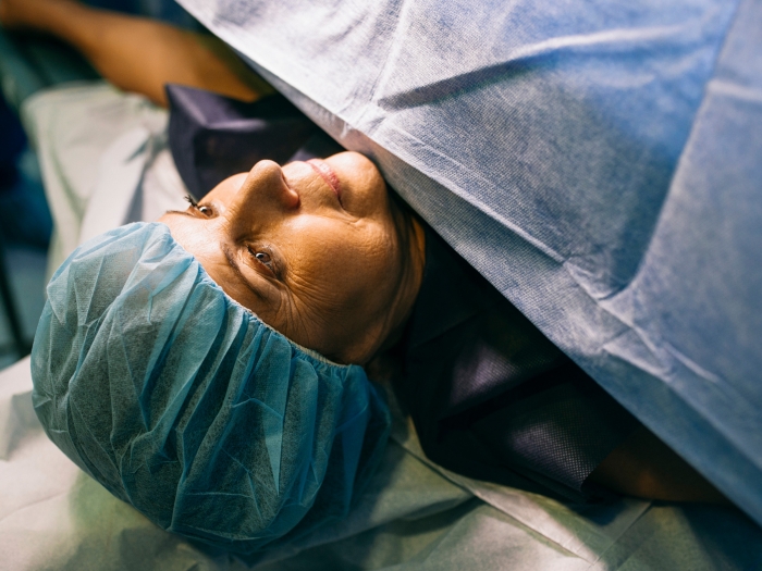 woman laying down and sheet over going into surgery