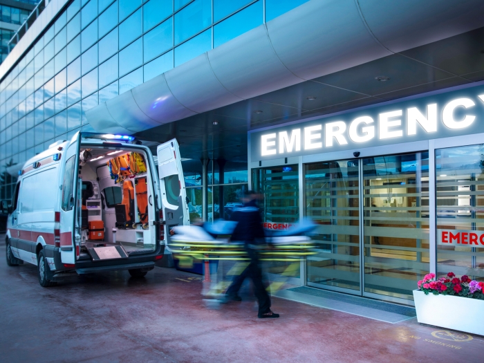 emergency room front doors with sign and blurred motion of people and a vechile