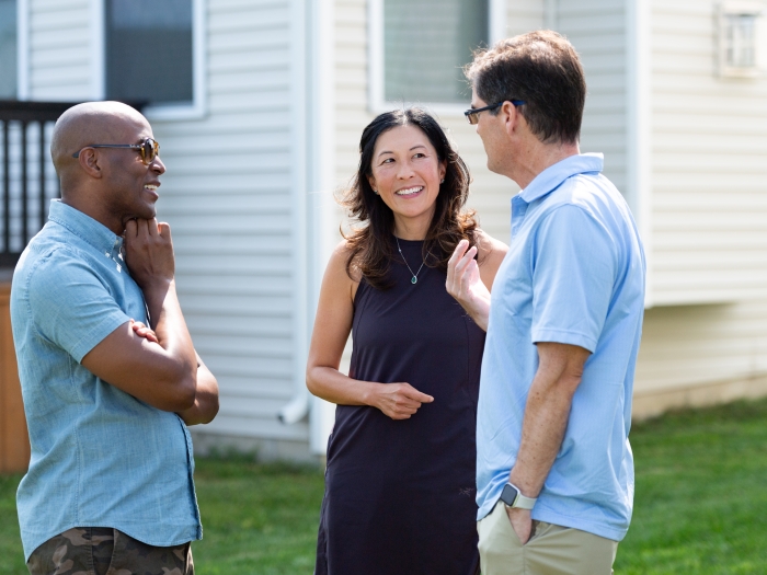 Three faculty members outside in a yard talking in a circle