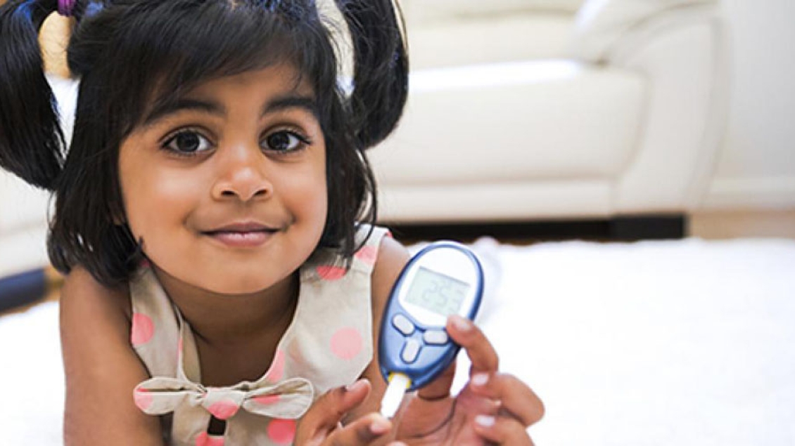 A young girl with pigtails holds a medical testing device.