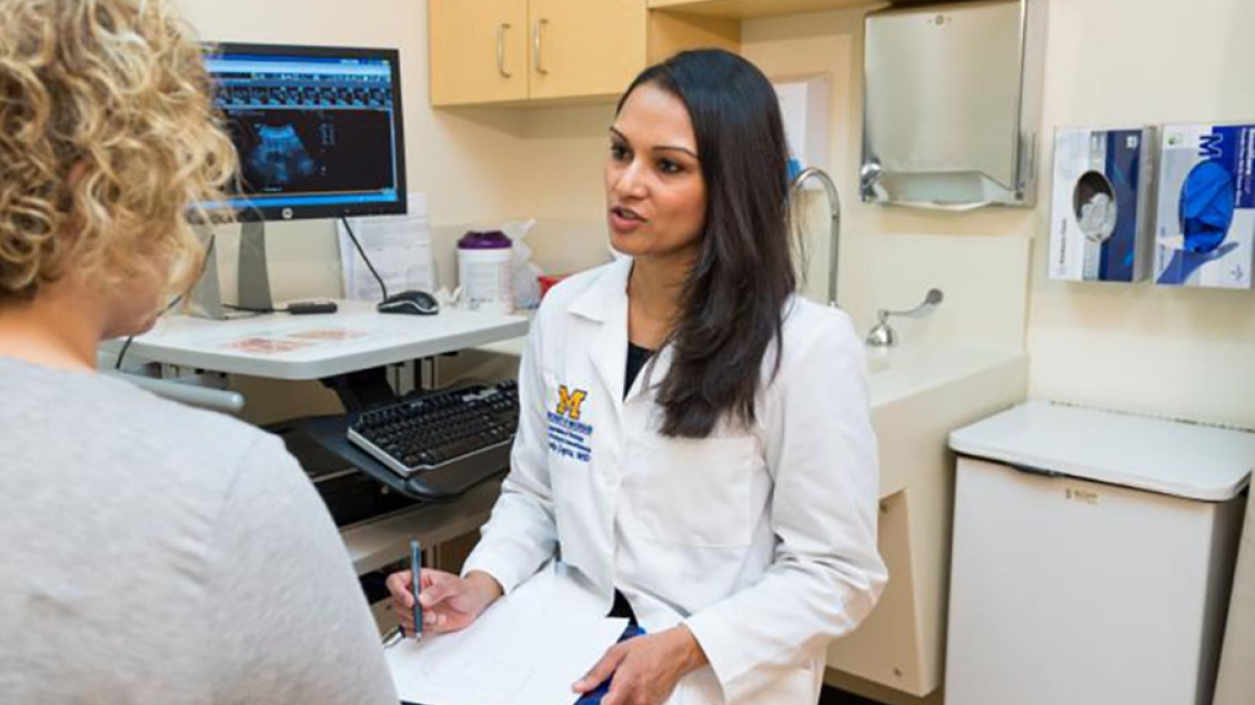 A doctor talks with a patient in an exam room.