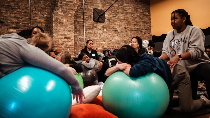 Diverse youth lounging on large exercise balls with brick wall in background