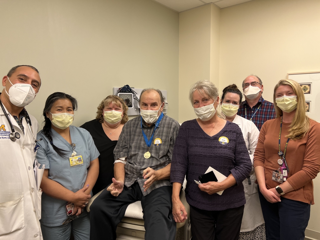 Staff standing around patient and bed with masks on