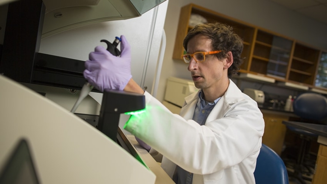 Carl Koschmann, M.D., works in a lab using a microscope