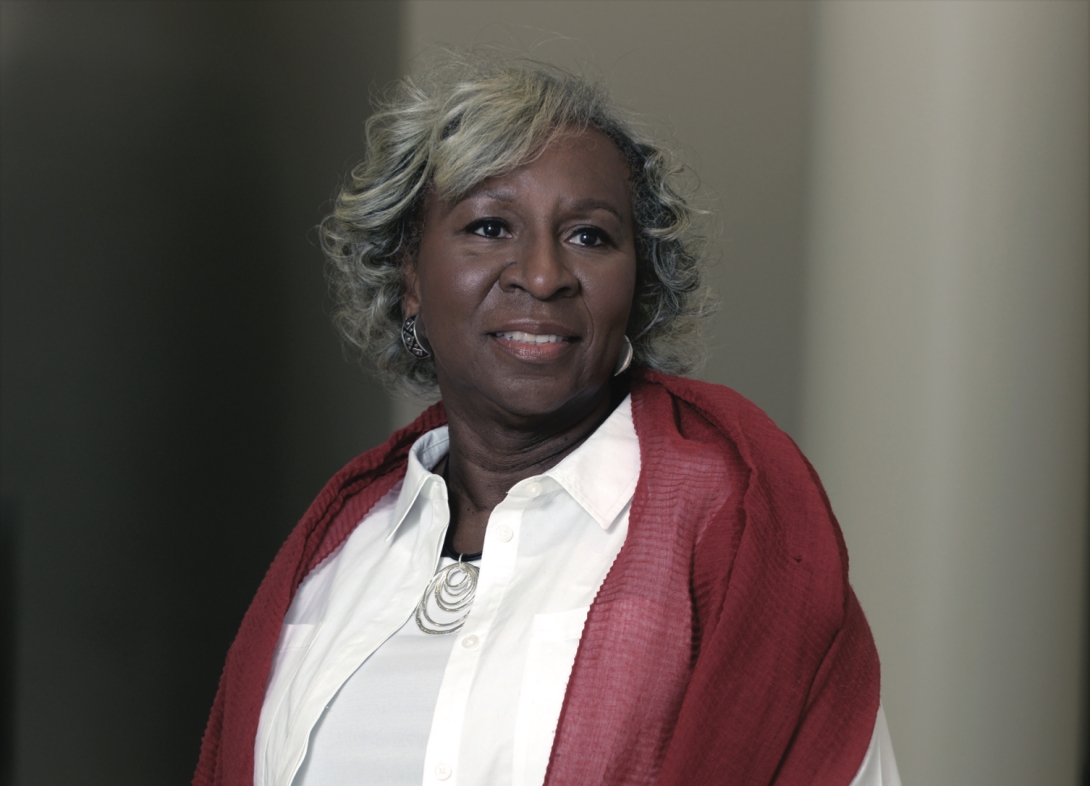 Portrait of Veleria Banks. She is wearing a white shirt with a red shawl draped over her shoulders. 