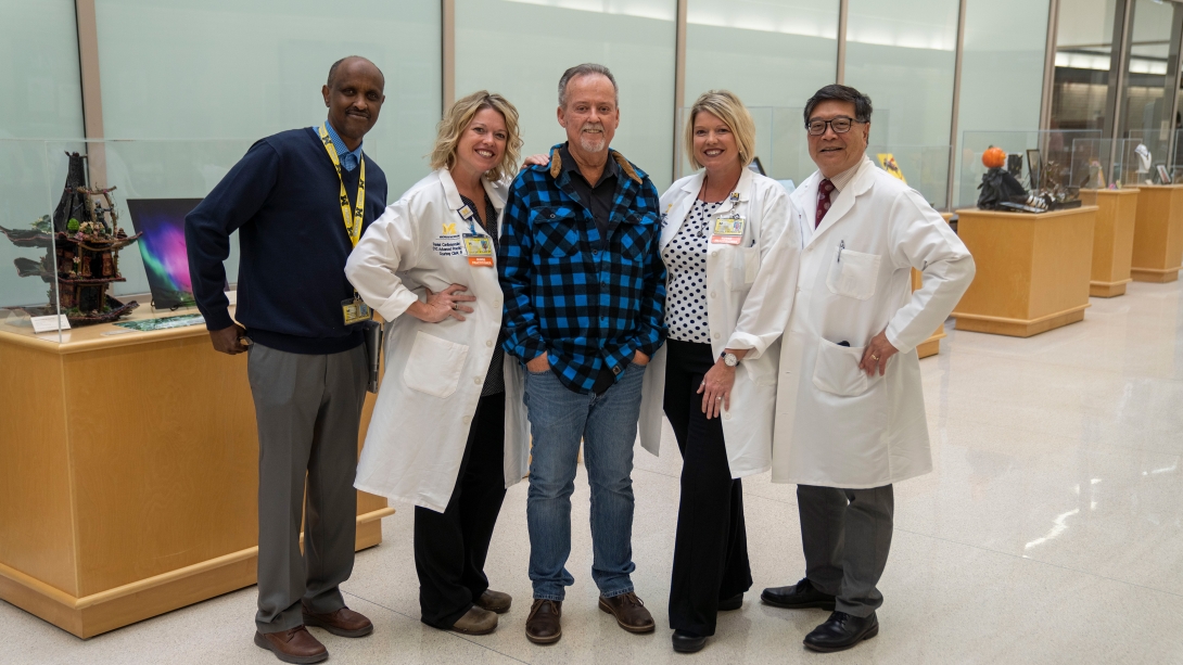 group clinicians with patient in middle posing and smiling